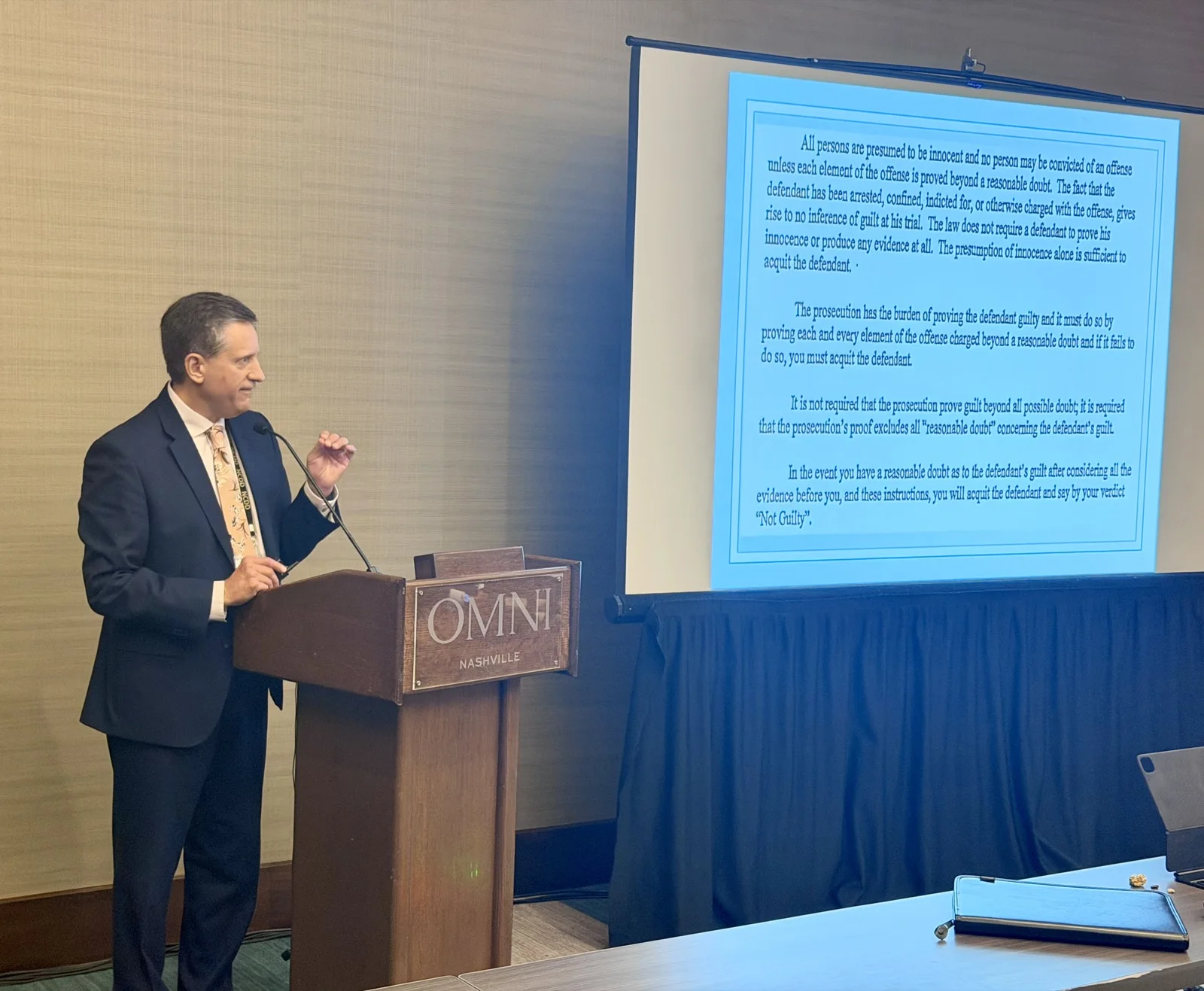 Phillip Goff delivering the closing demonstration at the Omni Nashville, with the reasonable-doubt jury instruction projected behind him